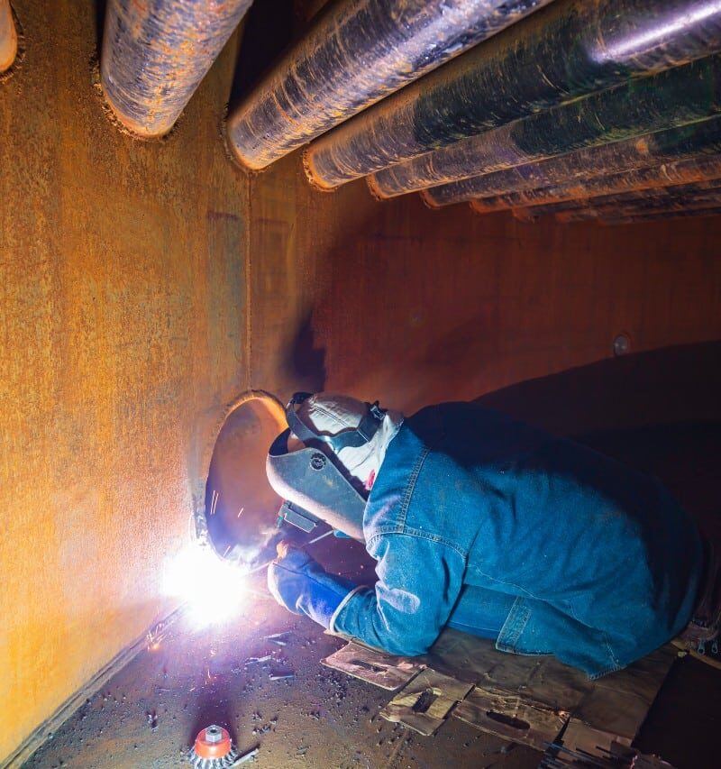 welding male worker metal is part machinery plate tank beam pipe construction flash spark inside confined
